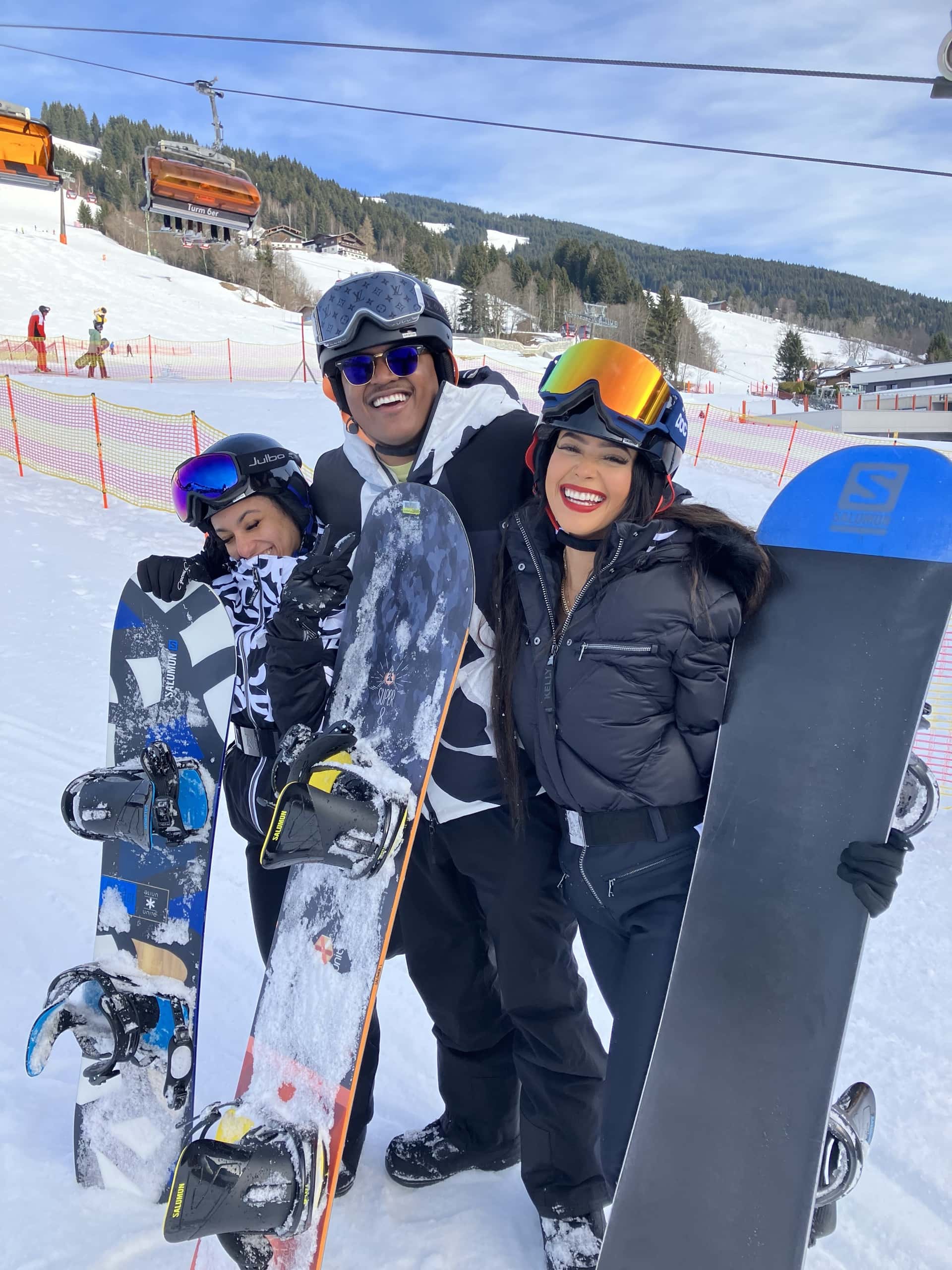 Guests on the slope with their boards, lift and blue sky behind them